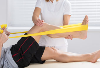physiotherapist with patient using exercise band