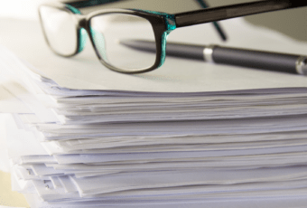 stack of paperwork with glasses