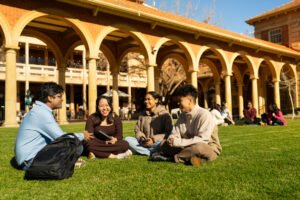 university of adelaide students sitting on grass in front of building