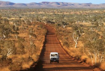 a truck driving down a red road in the australian outback
