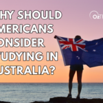 person holding australian flag looking out to the ocean at sunset