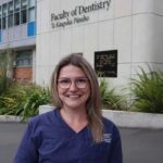 young woman with glasses standing outside a building that says Faculty of Dentistry