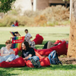 university students sitting on red bean bag chair on a lawn