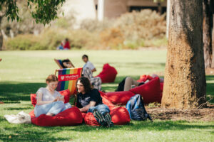 university students sitting on red bean bag chair on a lawn